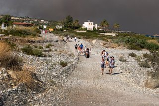Des personnes quittent le village de Kiotari, menacé par les incendies sur l'île de Rhodes.